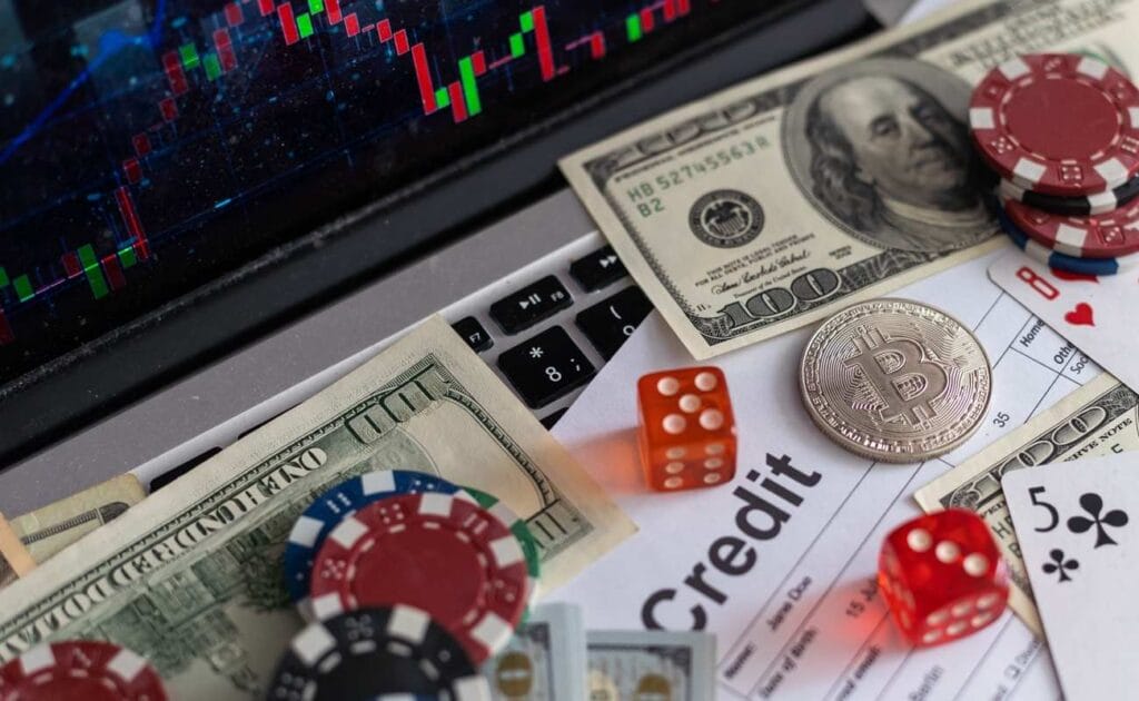 Dollar bills, poker chips, die, and playing cards on a laptop keyboard