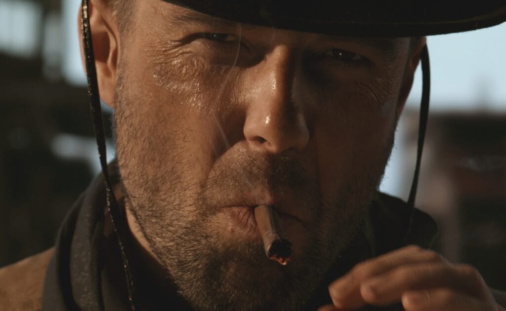 A cowboy smokes a cigar