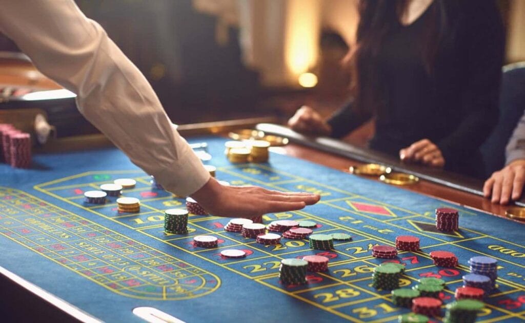 A casino dealer laying the chips out on a craps table.