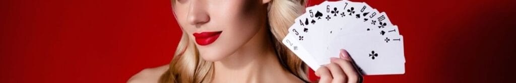 A woman wearing red lipstick holding up a stack of fanned out playing cards.