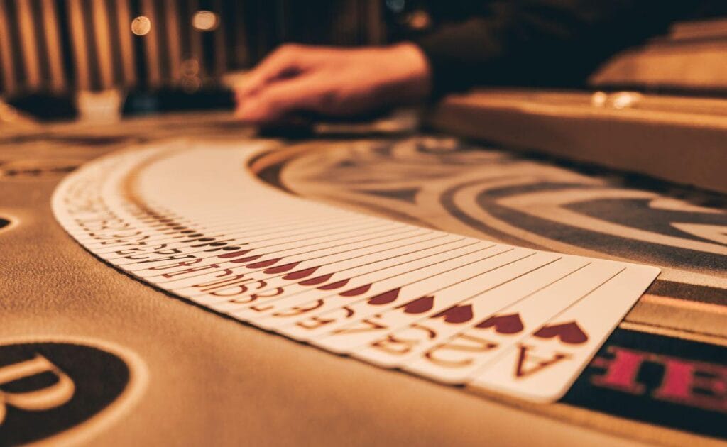 Croupier fanning out a deck of cards on a leather poker table.