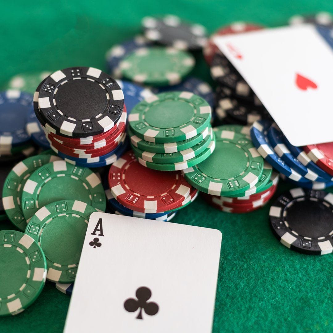 An ace sitting next to scattered poker chips.