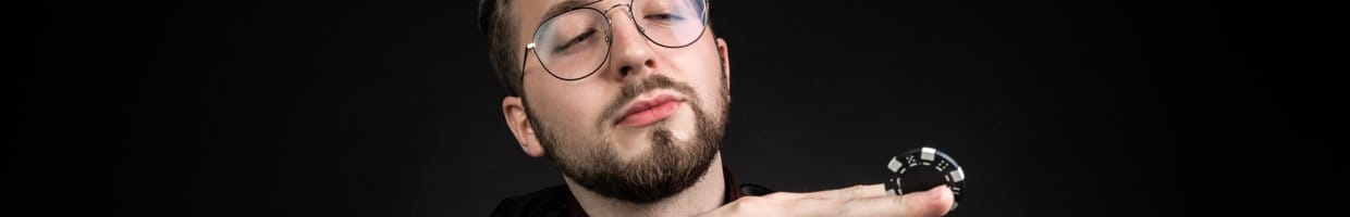 A poker player looks at a poker chip they have pinched between their middle and index fingers.