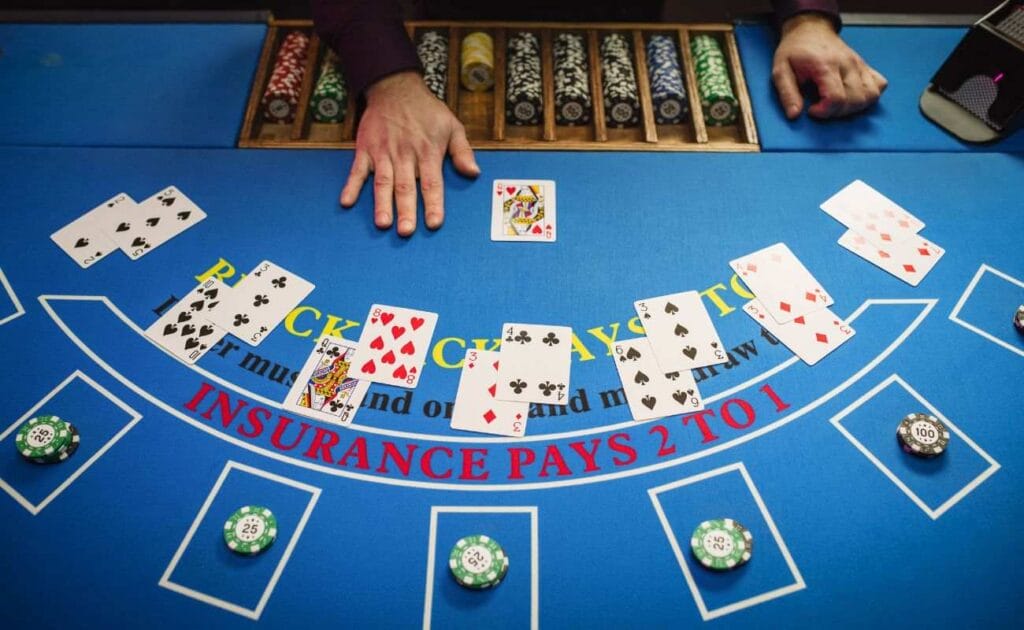 Game of blackjack in session with stacks of poker chips and playing cards laid out.