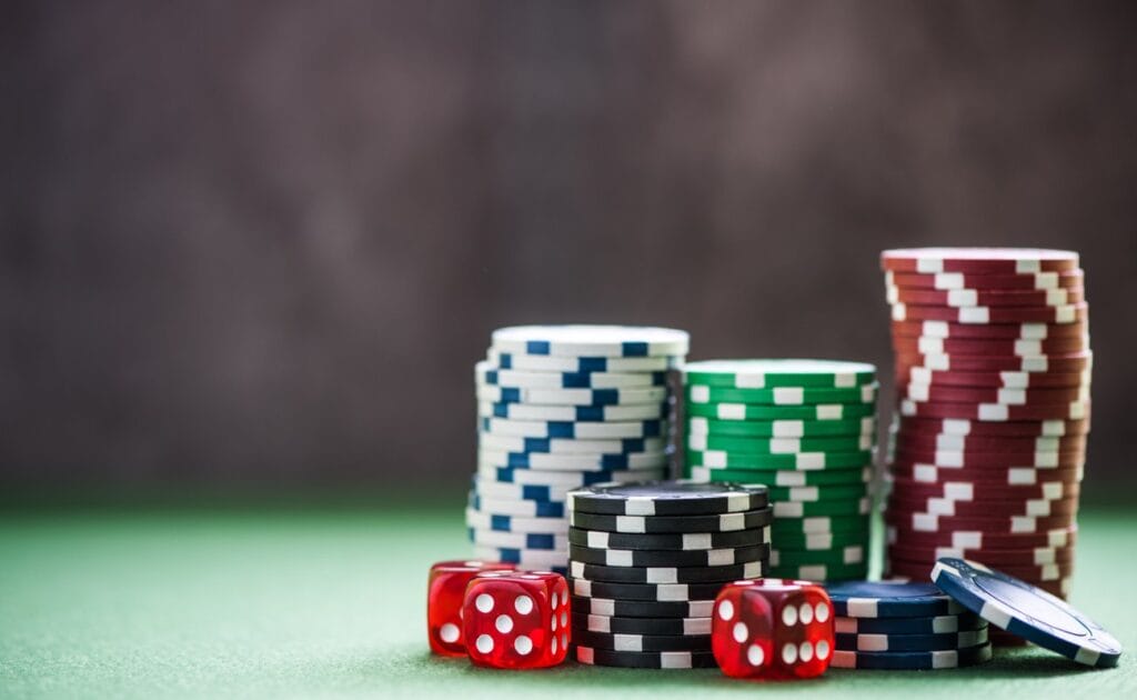 Stacks of casino chips with dice next to them.