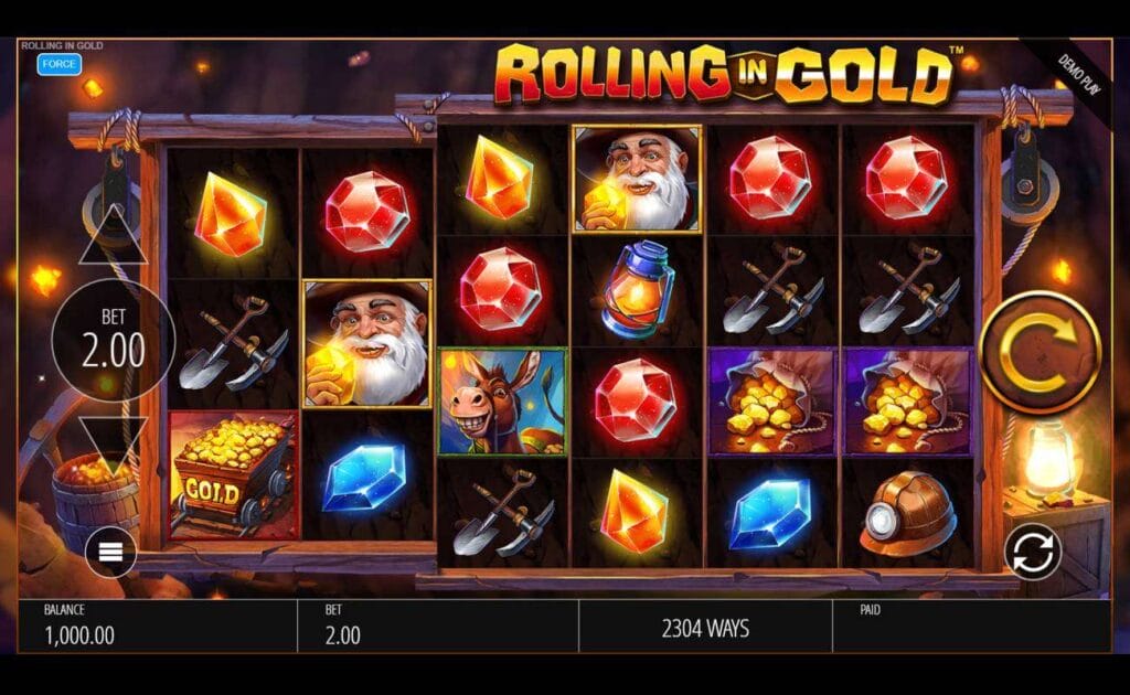 A screenshot of the Rolling in Gold reels. The background for this game is a shaft deep within a mine, with a lantern on the right lighting up the dark, a barrel of gold nuggets on the left. The reel symbols, set in wooden planks, include a mining cart, shovel and pickax, a lantern, a mining helmet, a prospector inspecting a gold nugget, a donkey, and different shaped and colored gems.