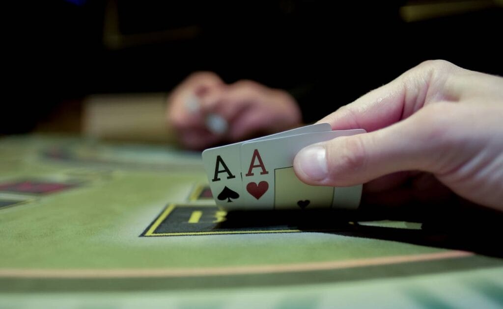 A poker player checking their hole cards. They have two aces.