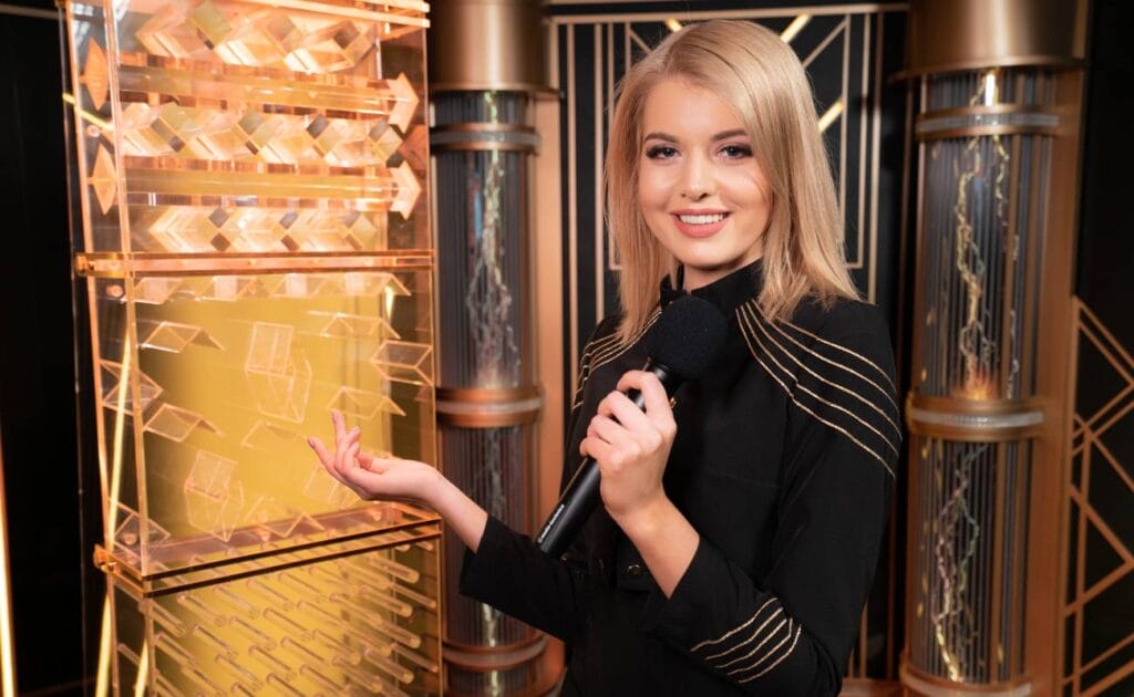 The Lightning Dice live dealer game. The game host holds a microphone and stands in front of the transparent game tower.