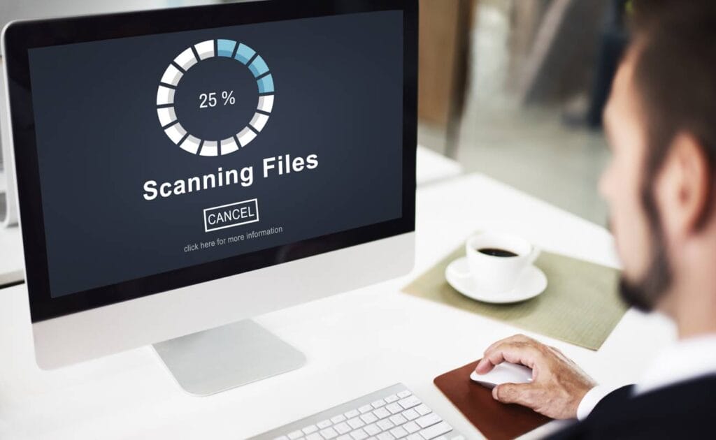 A man using his computer while it scans its files.
