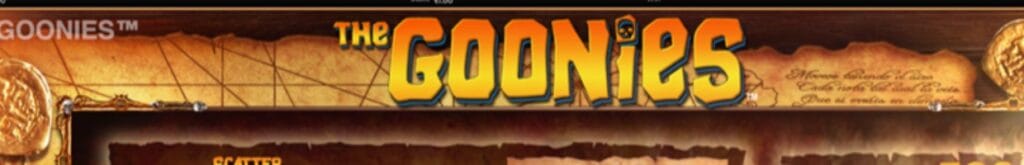 The Goonies online slot game logo in yellow and blue. The background shows a treasure map and gold coins on a table.