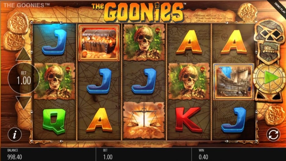 The Goonies online slot game with playing cards, skeletons, a ship, and a treasure chest on the reels. The background contains a treasure map and gold coins.