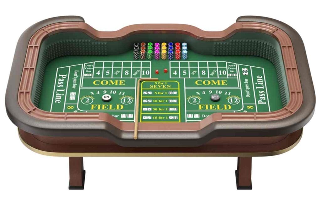 An overhead view of an online craps table ready to be played. The felt is green with yellow and white text. There are stacks of differently colored casino chips at the top of the table. The green felt is bordered by a brown outline of a table.