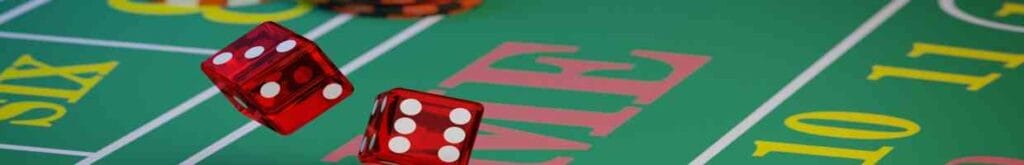Close-up of two red dice being rolled onto a craps table.