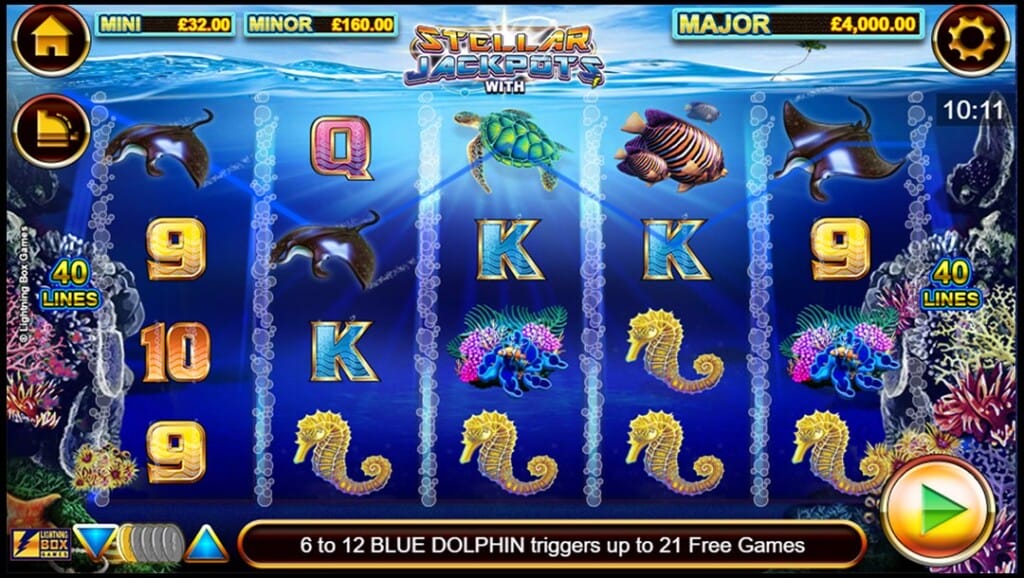 A screenshot of the slot reels in Dolphin Gold Stellar Jackpots. In the foreground are five vertical reels set against a deep blue ocean backdrop filled with coral, seaweed, and sunbeams that filter through the water. Each reel displays colorful symbols, including seahorses, turtles, dolphins, fish, and traditional playing card icons. At the top of the screen, the Mini, Minor, and Major jackpot prizes are displayed. The interface is visible along the top left, top right, and bottom of the slot reels. A banner along the bottom states, “6 to 12 BLUE DOLPHIN triggers up to 21 Free Games.”