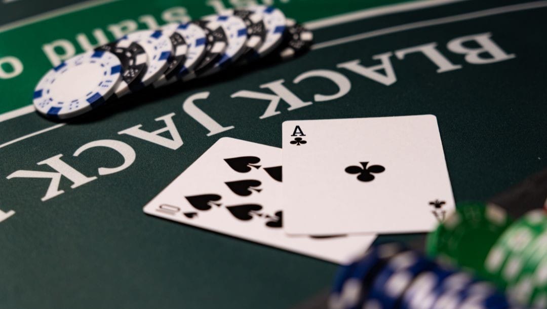 Blackjack table with poker chips and two playing cards — ace of clubs and eight of spades — showing a winning hand.