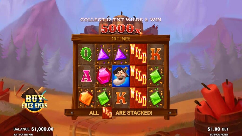  A screenshot of the slot reels in Big Boom Riches. The reels are set against an empty field in front of a forest with mountains in the distance. Mining cart tracks head back through the field. The slot reels have a variety of mining-related symbols, including gems, wilds, the prospector, and playing card symbols.
