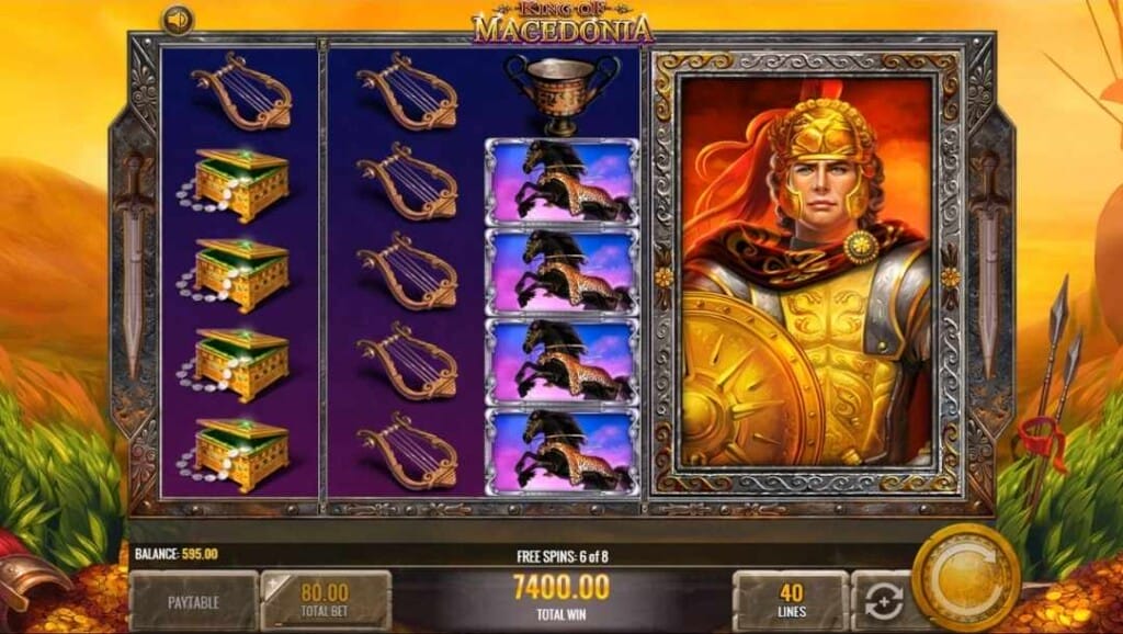 King of Macedonia bonus game screen with the background scene transformed to sunset colors, possibly depicting an ancient battlefield with pieces of armour and weaponry scattered over mounds of gold. The reels feature Alexander the Great as a gigantic wild, locked in place, covering two full reels.