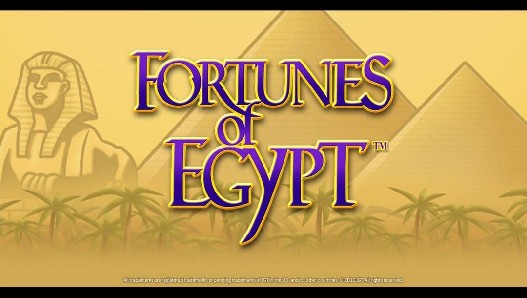 The Fortunes of Egypt banner. The backdrop is rendered in an illustrative style, showing palm trees with the Sphinx and pyramids behind them. Sand fills the air, giving the scene a hazy appearance. In the foreground, the game title is rendered in gold and purple font.