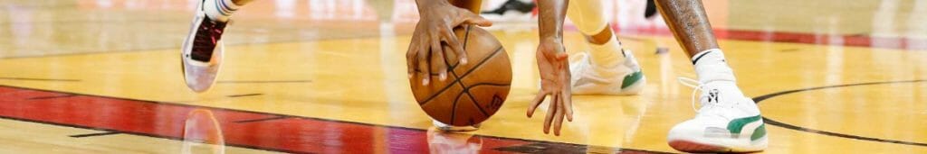 Two basketball players reaching for ball on court