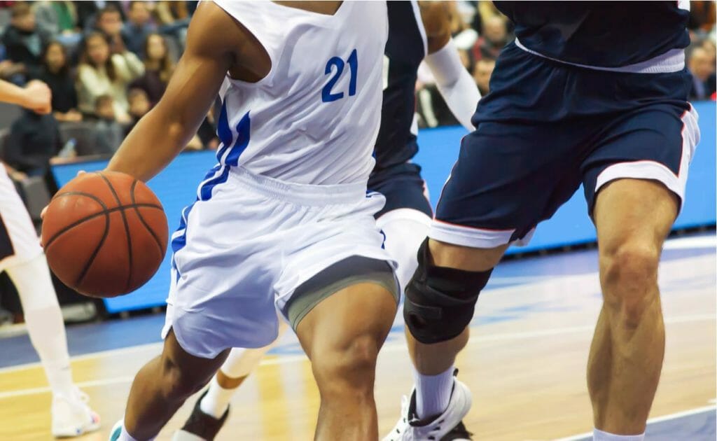 Two basketball players in white and blue uniforms battling for the ball