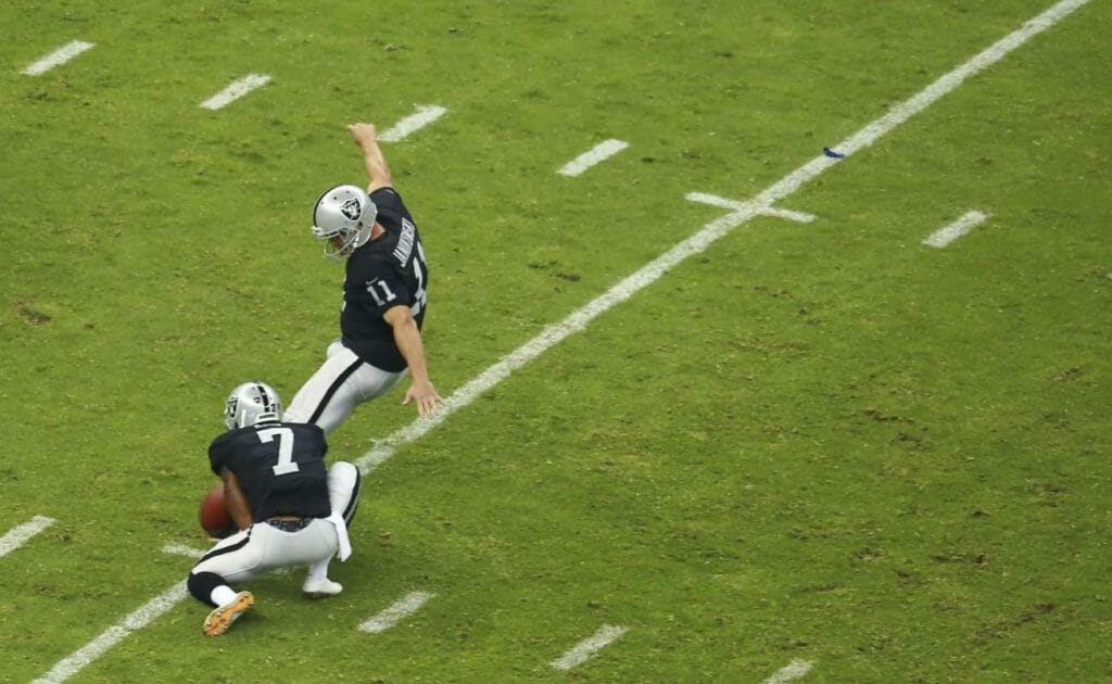 Sebastian Janikowski kicks football on the field