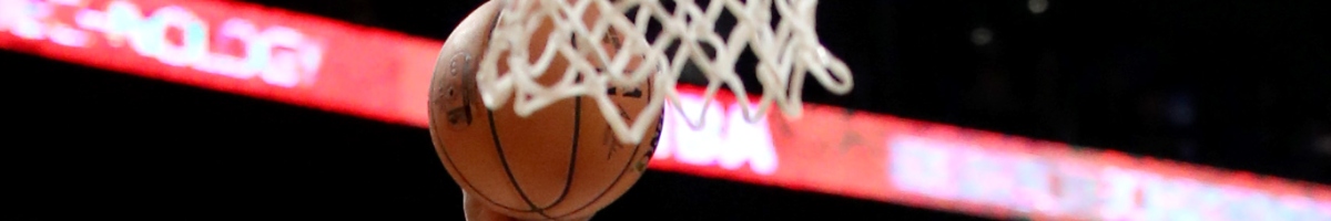 Hand on basketball thrown behind basketball net