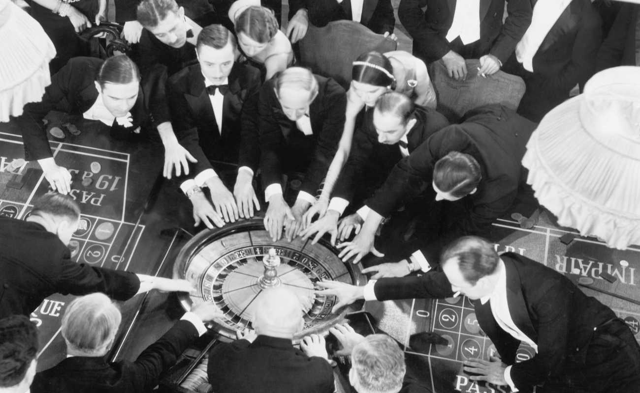 vintage black and white photo of men crowding around a roulette wheel