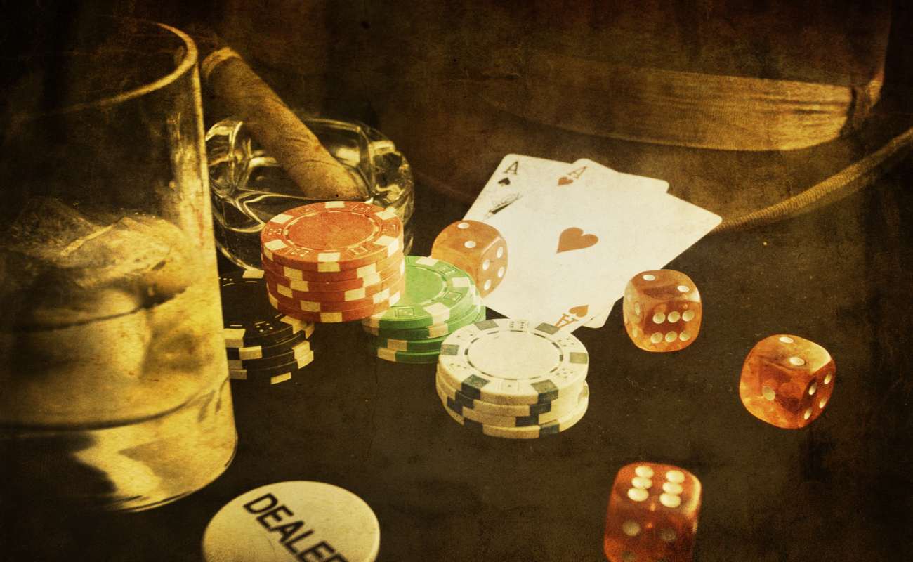 vintage photograph of poker chips and playing cards next to glass of whisky