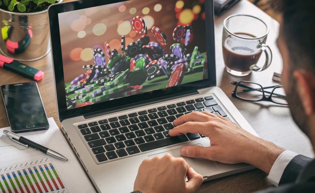 man using laptop with casino chips on screen concept of online gambling