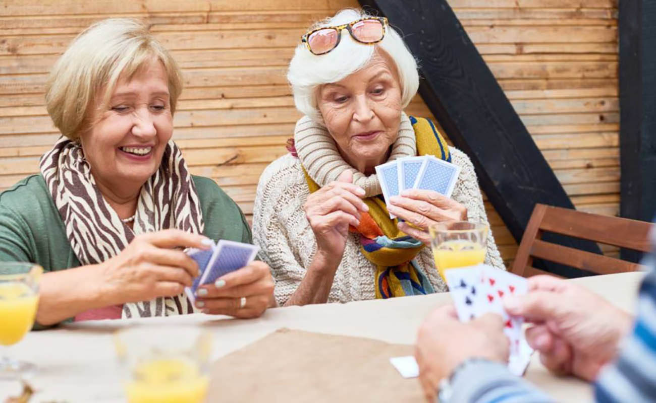 two seniors smiling and player poker