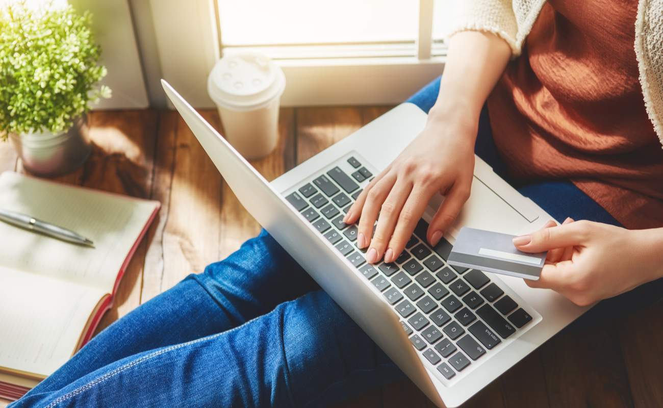 Woman holding credit card and using laptop computer