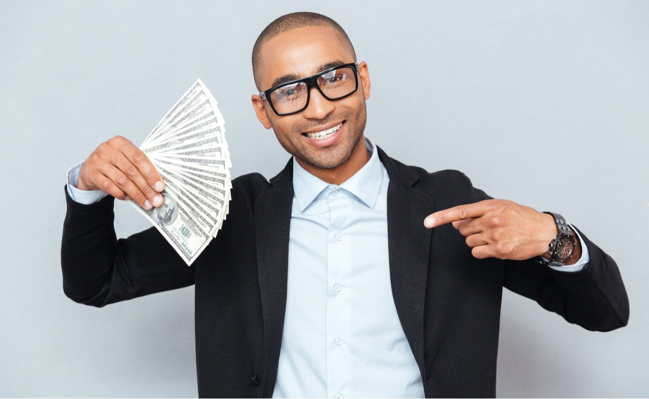 Happy young man holding dollars and pointing on it