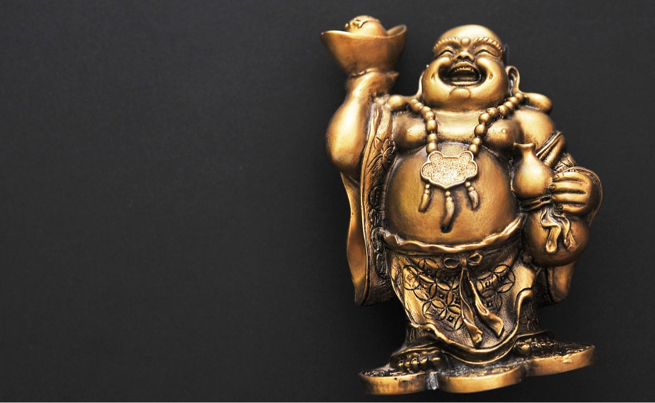 Golden laughing buddha statue on a black background