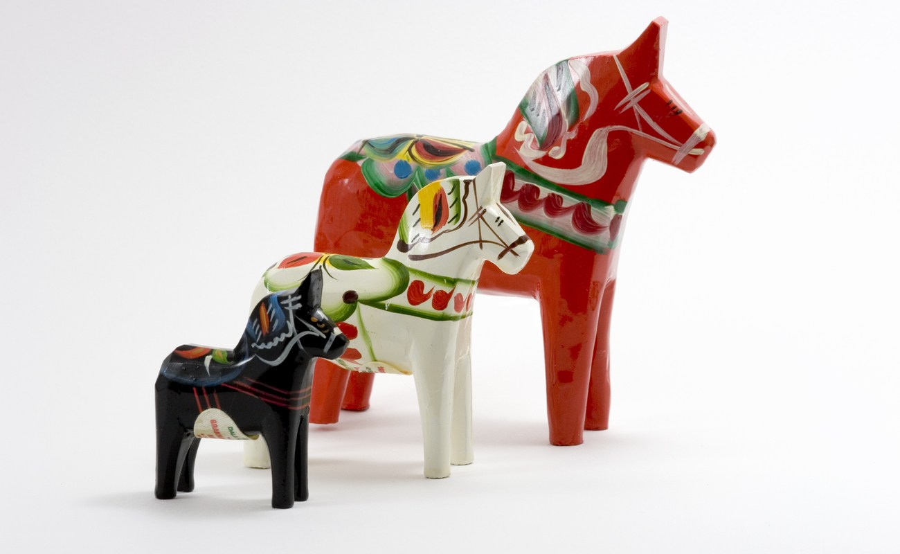 Three Swedish Dala Horses lined up on a white background