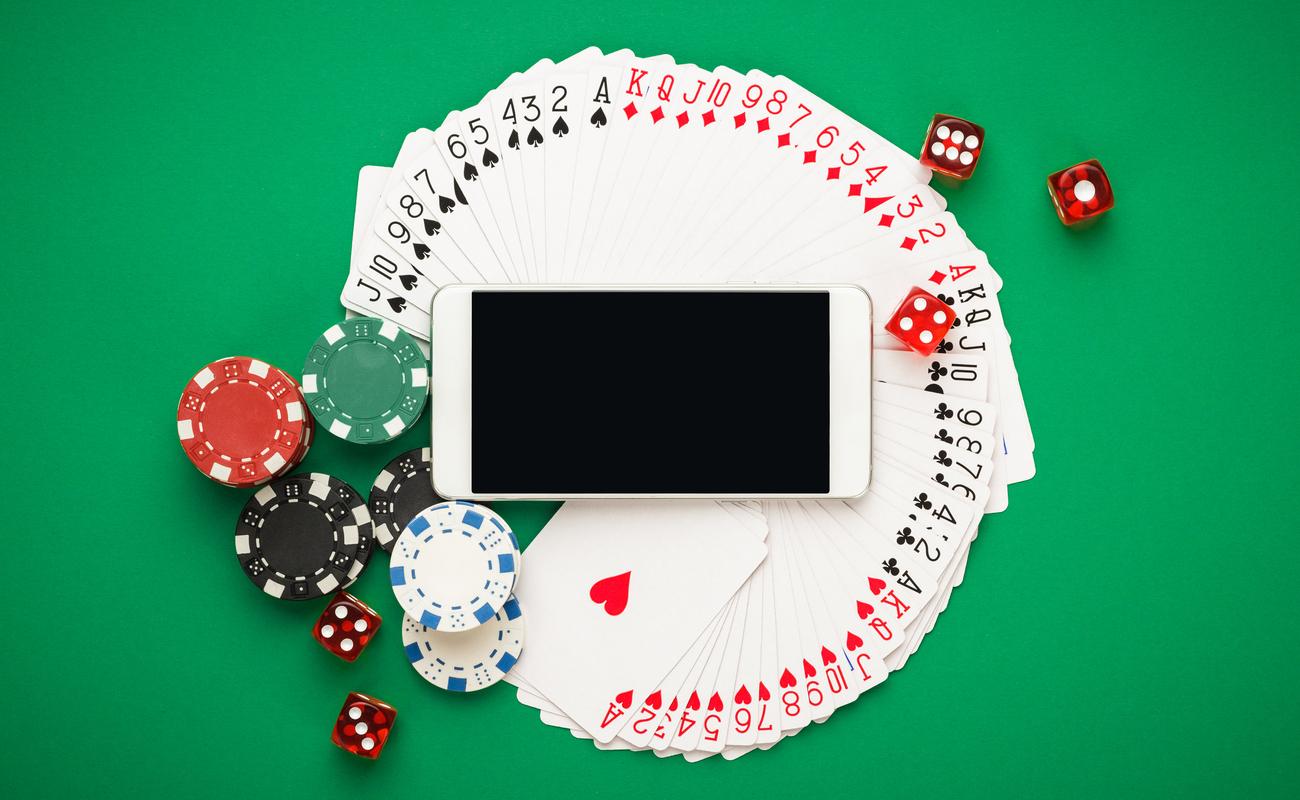 Playing cards, dice chips and smartphone on green table