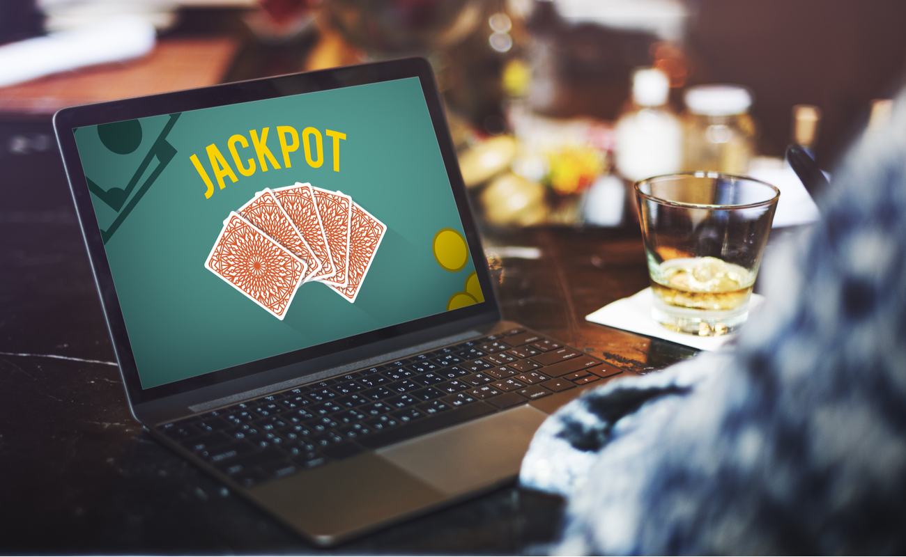 Gambling Luck Jackpot on laptop screen, drinks and lights in background