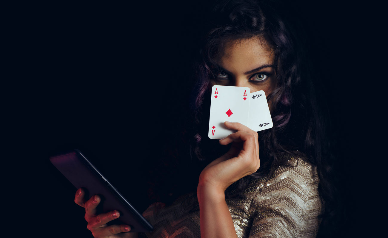 Mystic beautiful girl, covering face with cards and holding tablet in hand