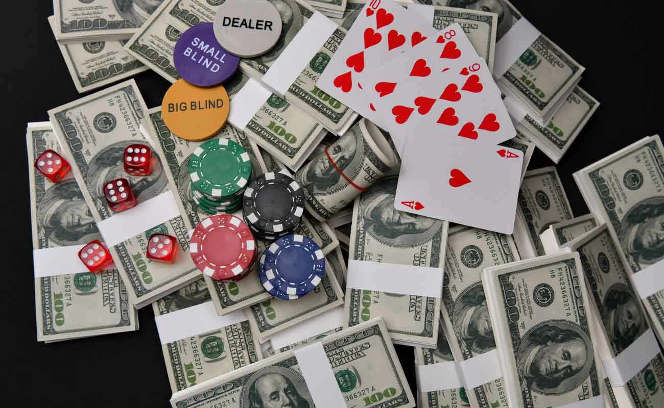 Gaming chips, poker cards, gaming dice and dollars on a dark background.
