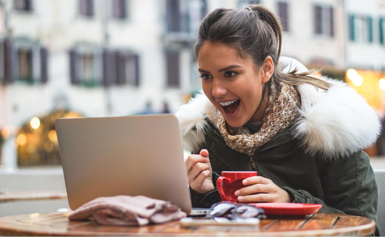 woman on her computer in a bar in city center drinks coffee while shopping online