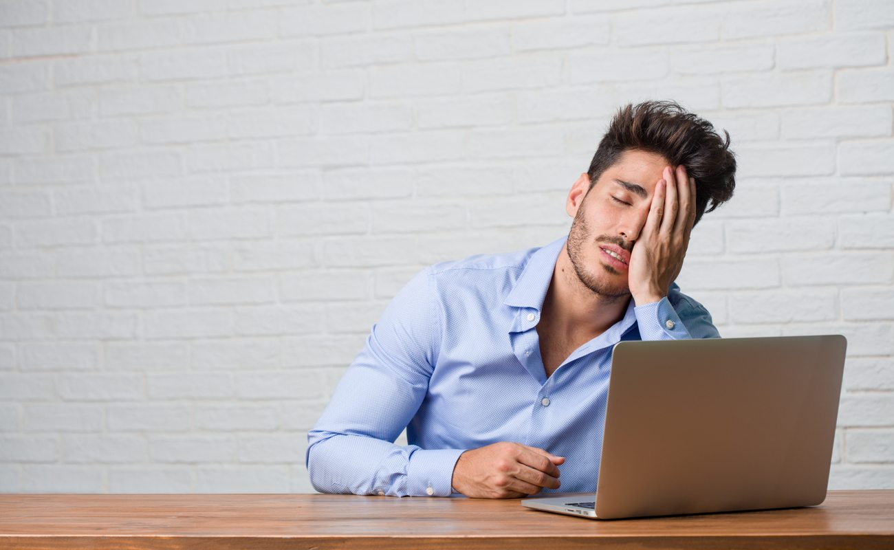 Young businessman sitting at laptop frustrated 