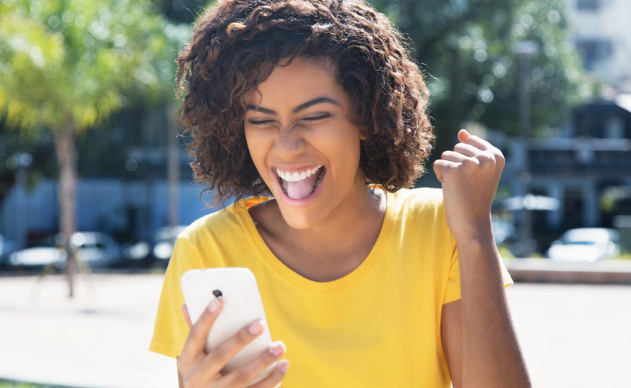Happy women celebrating online win while looking at mobile phone