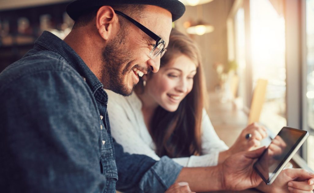 Closeup of young man and woman looking at a touch screen tablet and smiling