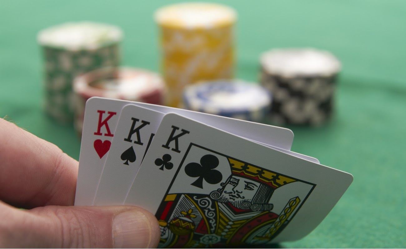 Poker hand showing three kings with poker chips in the background