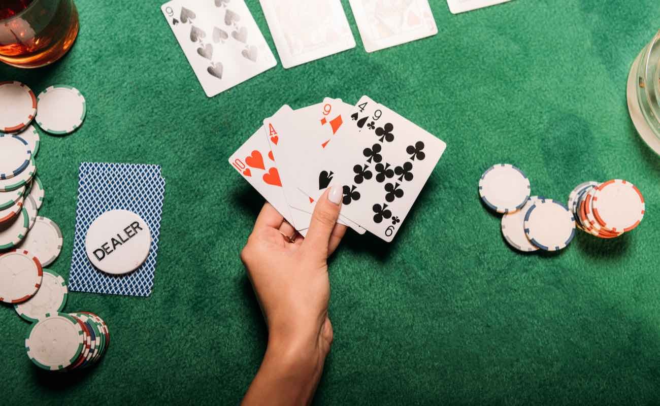 Cropped image of woman playing poker at table in casino and holding playing cards