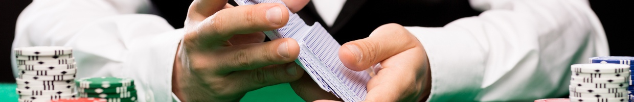 Casino dealer shuffles playing cards at a green felt table with chip stacks.