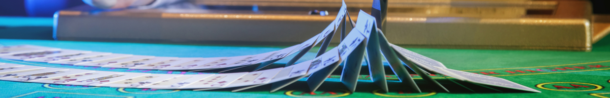 Professional croupier shuffling cards on a green felt casino table.