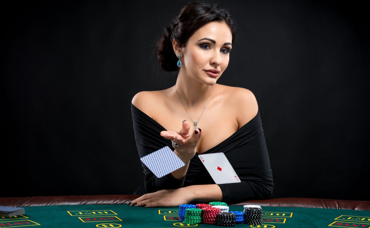 Woman sitting at gambling table with chips and throwing two cards.