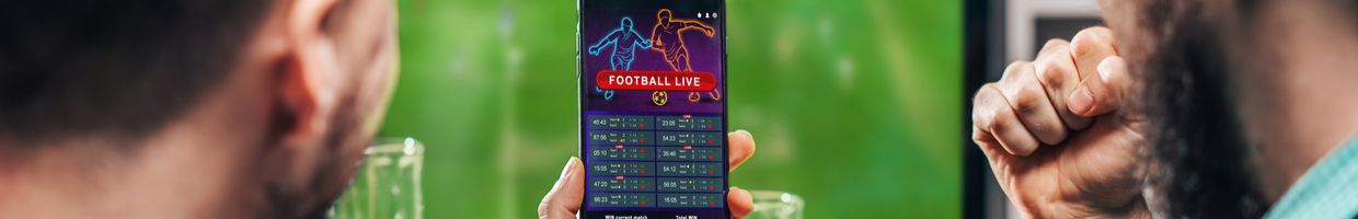 Two young bearded men celebrate online sports betting on their phones.