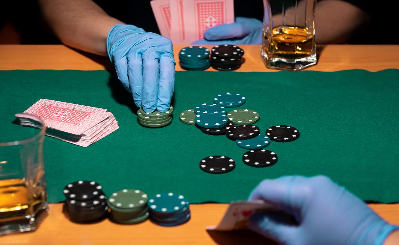 Two poker players enjoy a game while wearing gloves.