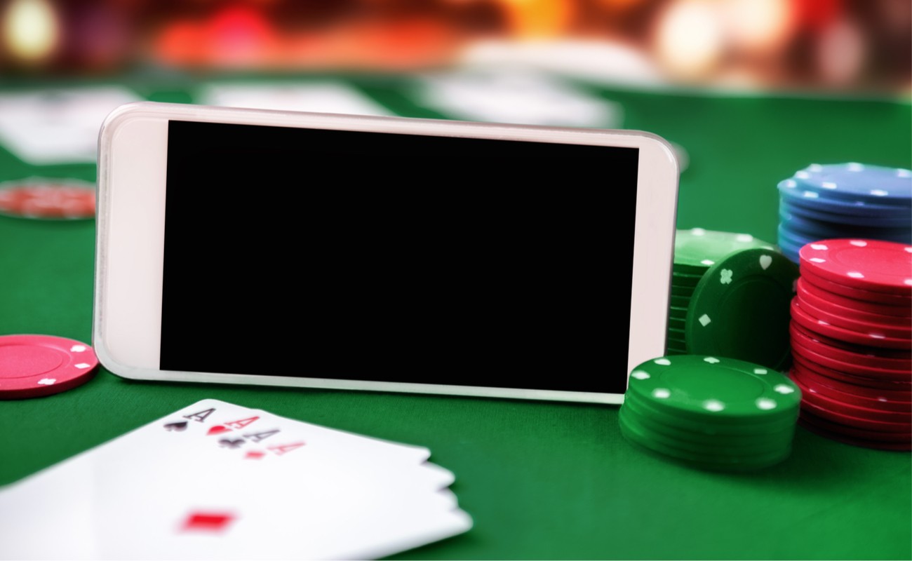 Smartphone with chip cards and four aces illustrating online poker.